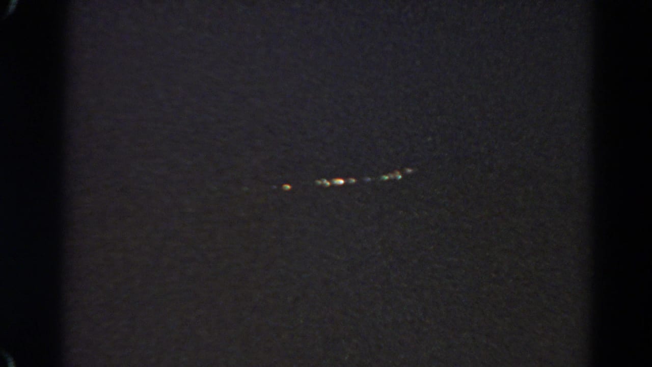 Distant lights glow softly in a dark nighttime landscape.