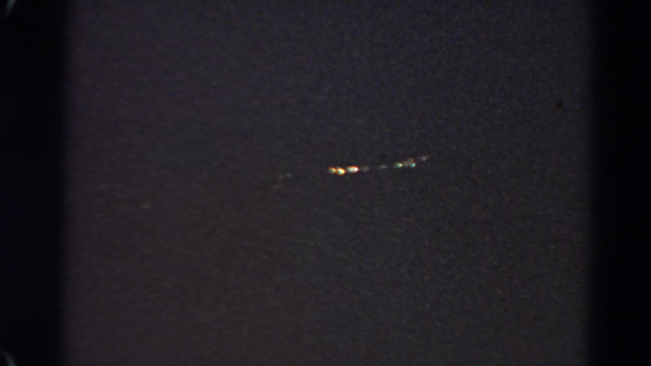 Grainy 1966 home-movie still with a small cluster of lights visible in the darkness at Silver Lake.