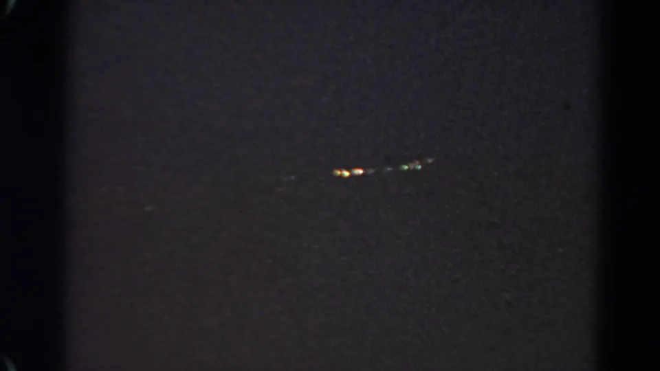 Grainy 1966 home-movie still with a small cluster of lights visible in the darkness at Silver Lake.