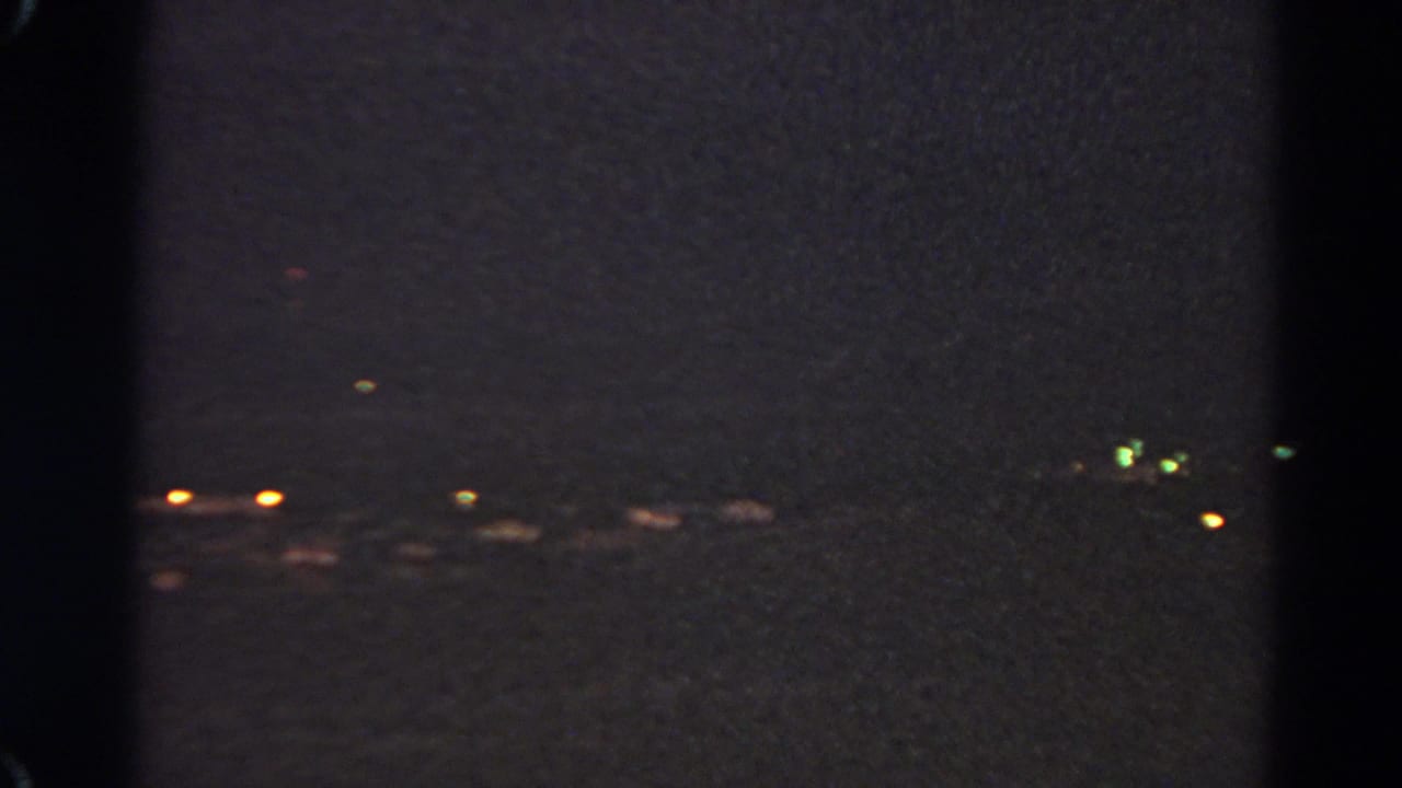 Dark night view with distant city lights and black film-frame borders.