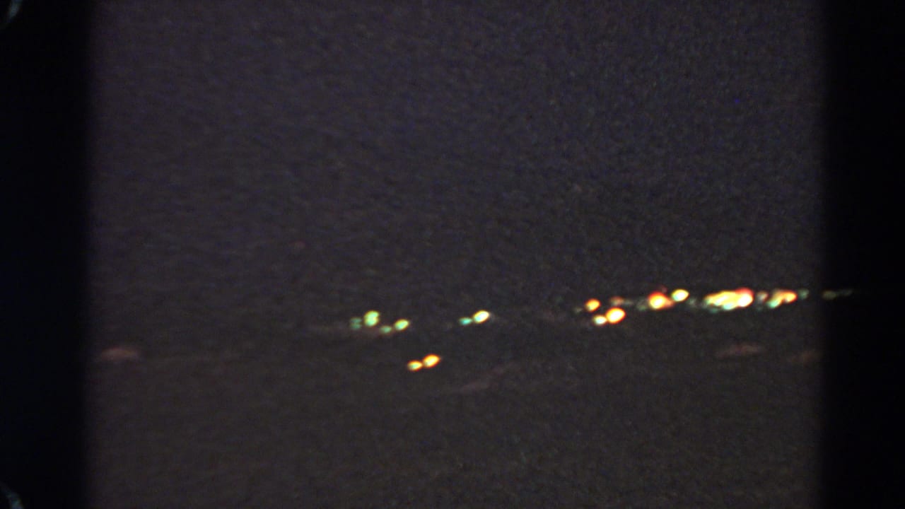 Panning 1966 Silver Lake night frame with scattered city lights, green glows, and underexposed dark surroundings.