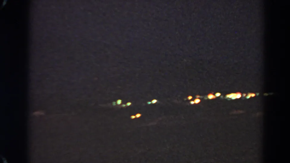 Panning 1966 Silver Lake night frame with scattered city lights, green glows, and underexposed dark surroundings.