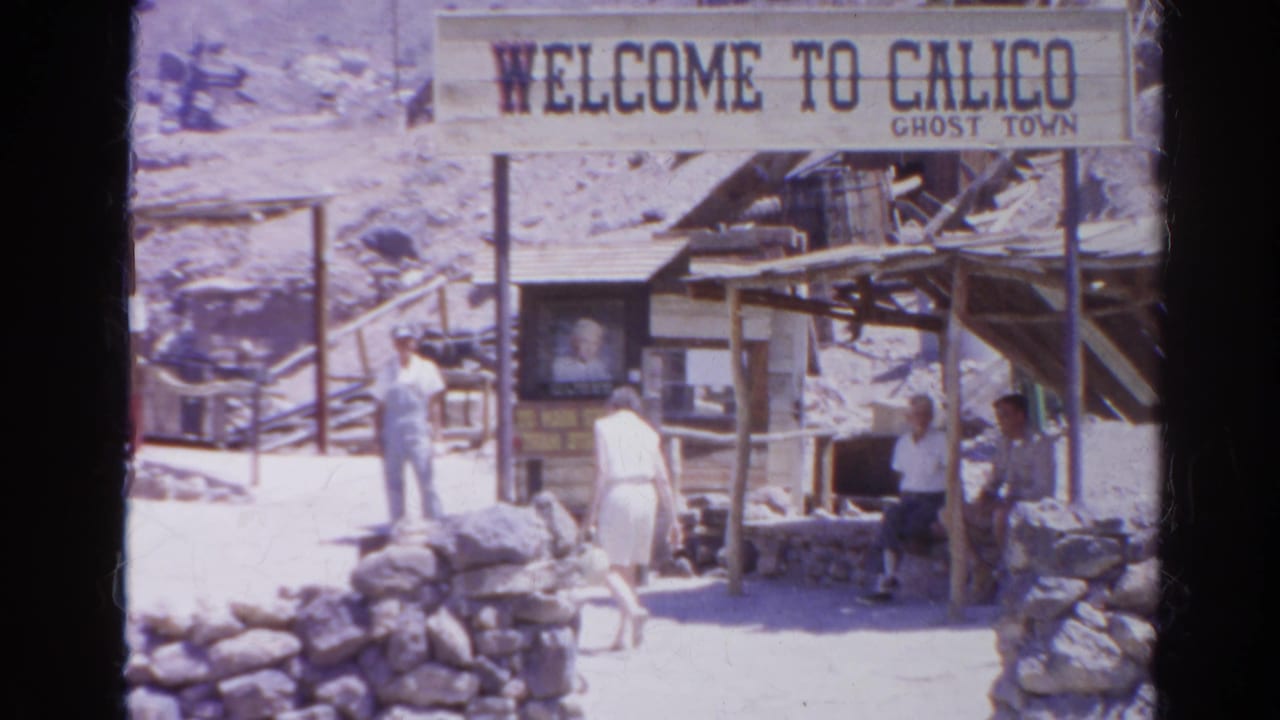 A closer 1966 home-movie view shows the Calico Ghost Town welcome sign, tourists, stonework, and timber structures in a desert setting.