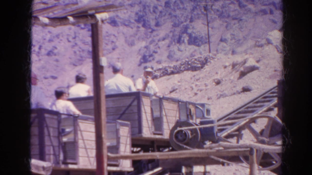 1966 Silver Lake, California frame showing an open ride cart with visitors, rail hardware, a vertical post, and arid rocky terrain.