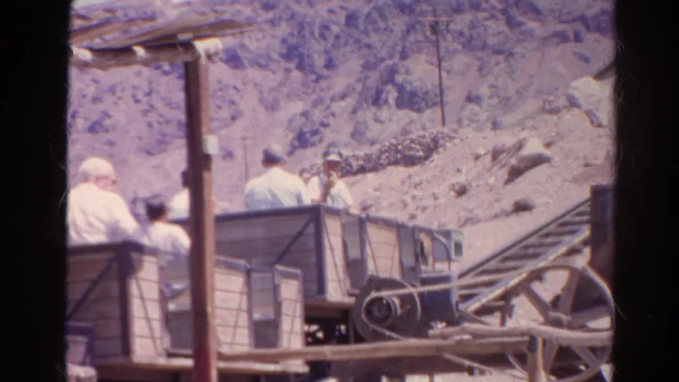 1966 Silver Lake, California footage showing several men riding a wooden cart up a dusty hillside with a pulley wheel and partial sign behind them.