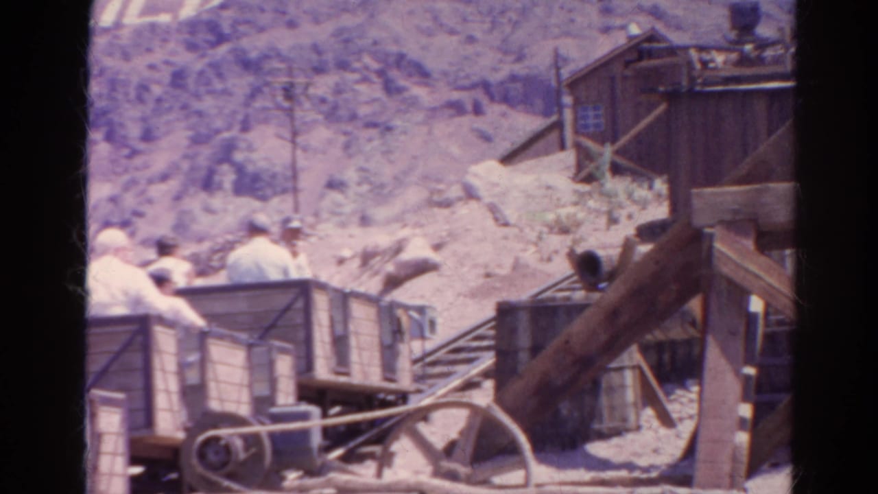 The final frame shows the cart and riders partly obscured by foreground framing, with a pulley wheel, rails, rocky slope, and wooden building visible.