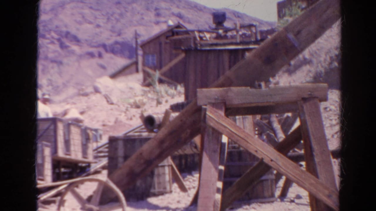 Wooden support beams and mining ride buildings beside a narrow track.