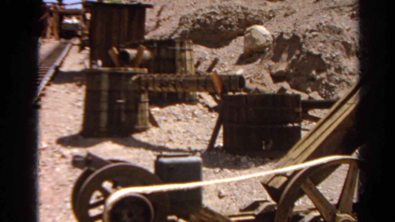 1966 Silver Lake footage showing wooden and metal equipment, barrels, and pipes in a dry rocky worksite area.