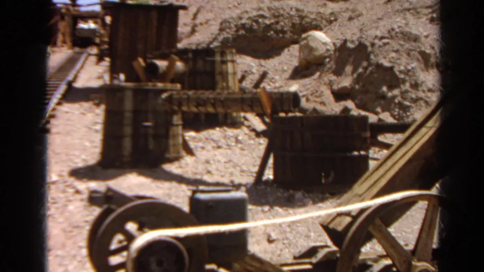 1966 Silver Lake footage showing wooden and metal equipment, barrels, and pipes in a dry rocky worksite area.
