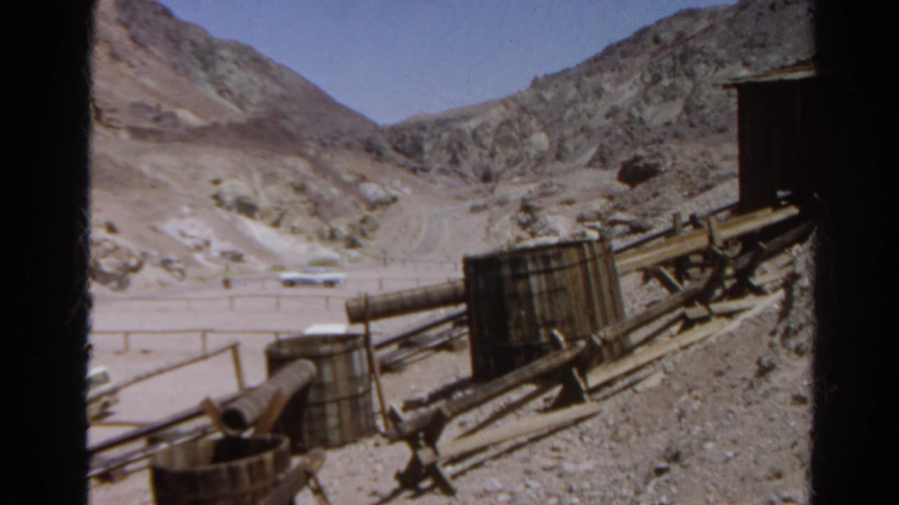 1966 Silver Lake, California 8mm frame showing mining carts, rails, timber supports, rocky slopes, and a gravel area below.