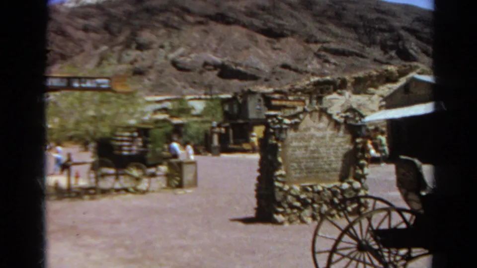 1966 Silver Lake, California home-movie frame showing visitors near a stagecoach and stone sign in a Western-themed town setting.