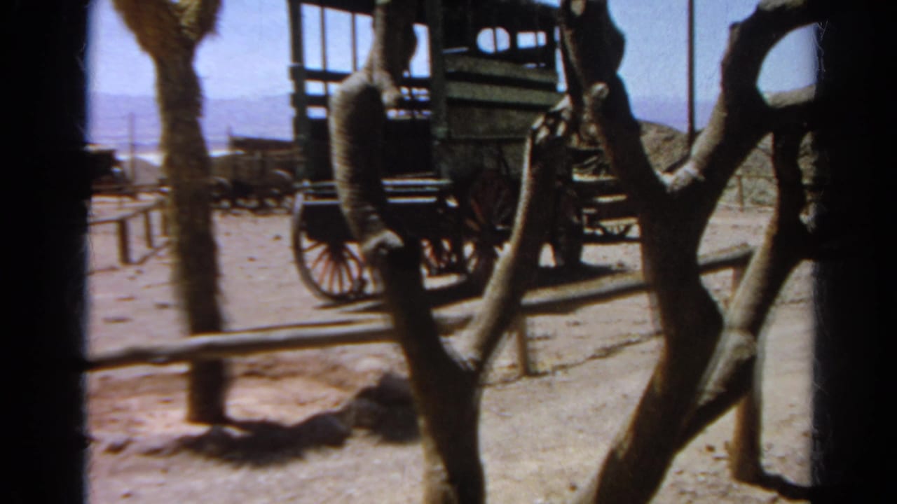 Silver Lake 1966 home-movie view of a carriage, bare tree trunk, low rail fence, and dusty arid terrain.