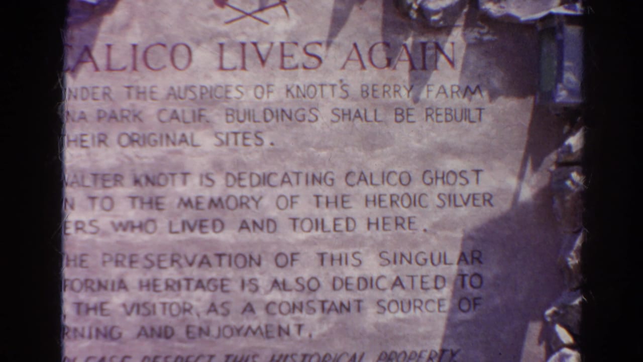 Close 8mm frame of a preservation sign headed Calico Lives Again, with partially readable text about rebuilding and dedication.