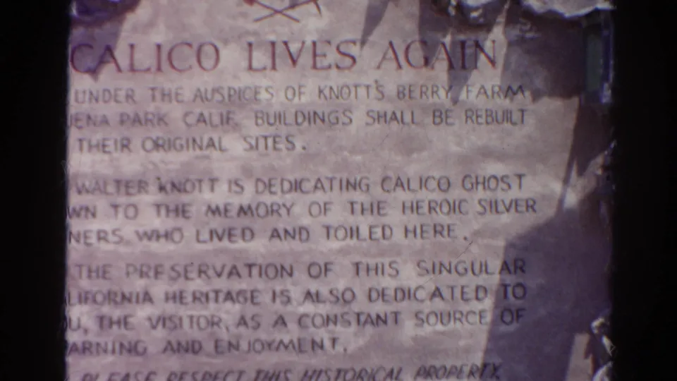 Final 1966 8mm frame of the weathered Calico marker, with dedication text, stone texture, and shadow along the right side.