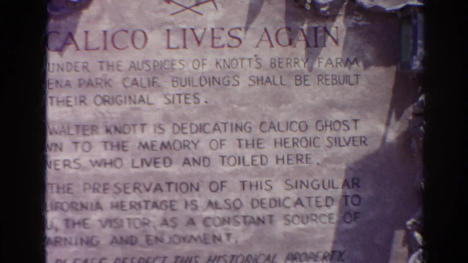 Close 1966 8mm view of a Calico Lives Again plaque describing preservation of a historic mining town site in California.