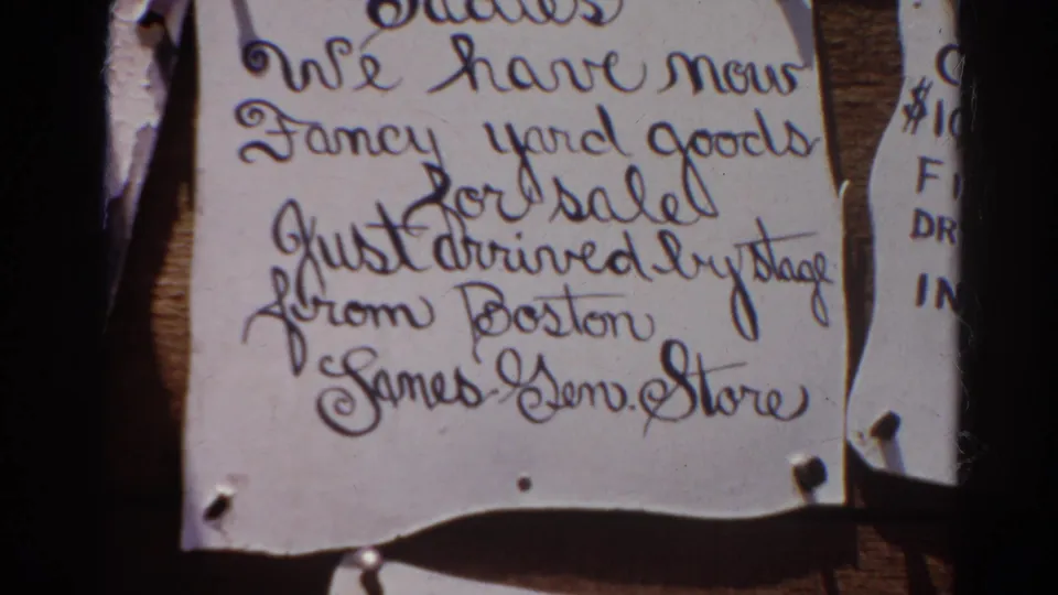 1966 Silver Lake home-movie frame showing torn handwritten notices on wood, including a partial yard-goods sale sign.