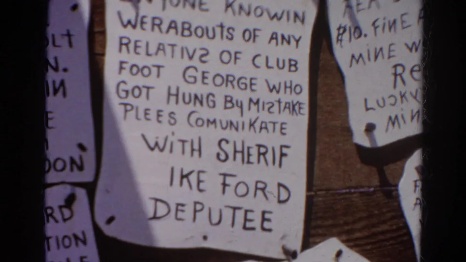 1966 Silver Lake 8mm frame showing handwritten notices on a wooden board, including text about Club Foot George and Sheriff Ike Ford.