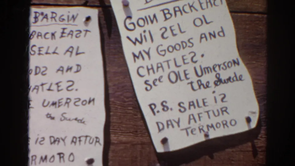 Silver Lake 1966 home-movie frame showing an angled handwritten notice about selling goods and chattel beside another cropped paper sign.