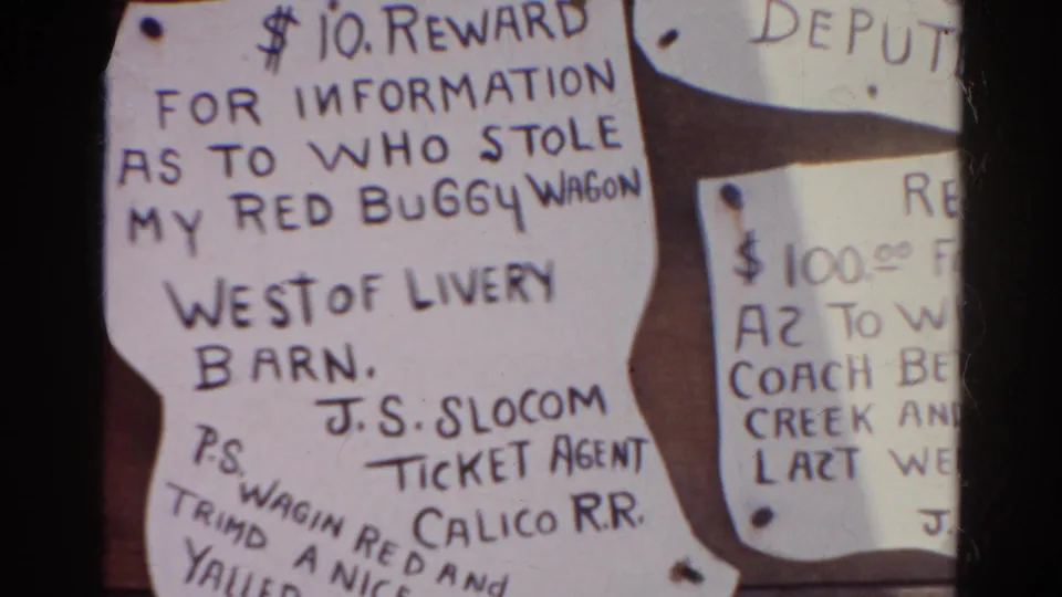1966 Silver Lake 8mm frame showing a $10 reward notice for a stolen red buggy wagon, signed by J.S. Slocom, Ticket Agent, Calico R.R.