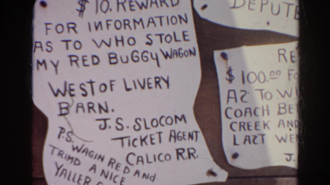 1966 Silver Lake home-movie frame showing a close-up of handwritten reward notices on a wood bulletin board, including a red buggy wagon notice.