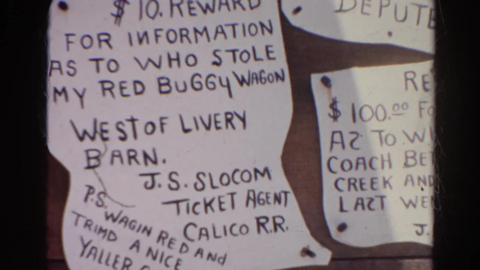 1966 Silver Lake home-movie frame showing a close-up of handwritten reward notices on a wood bulletin board, including a red buggy wagon notice.