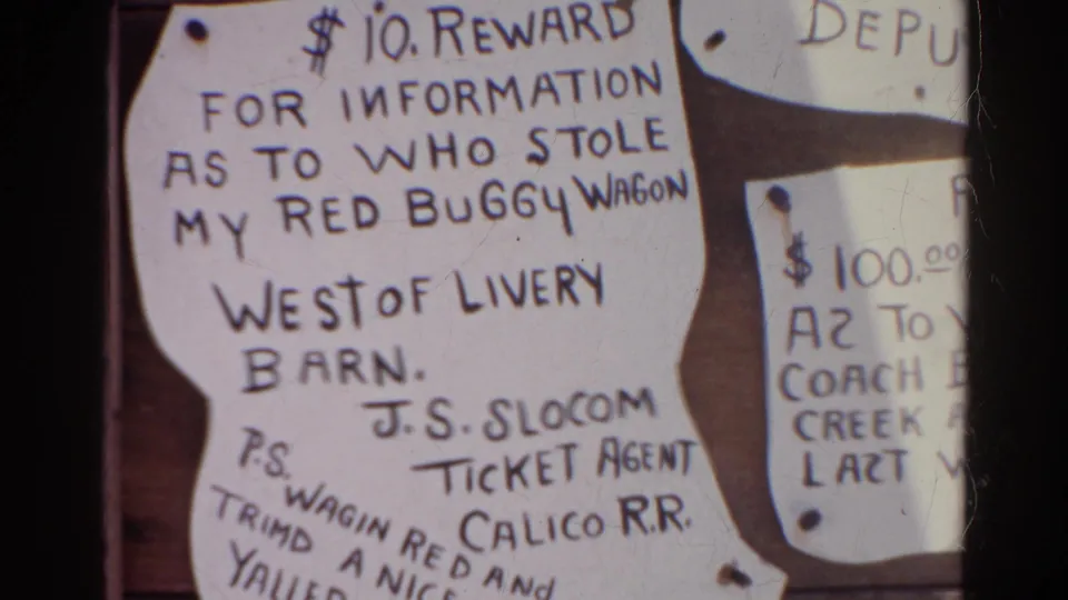 1966 Silver Lake frame with handmade reward signs on a bulletin board, including readable Calico R.R. and red buggy wagon text.
