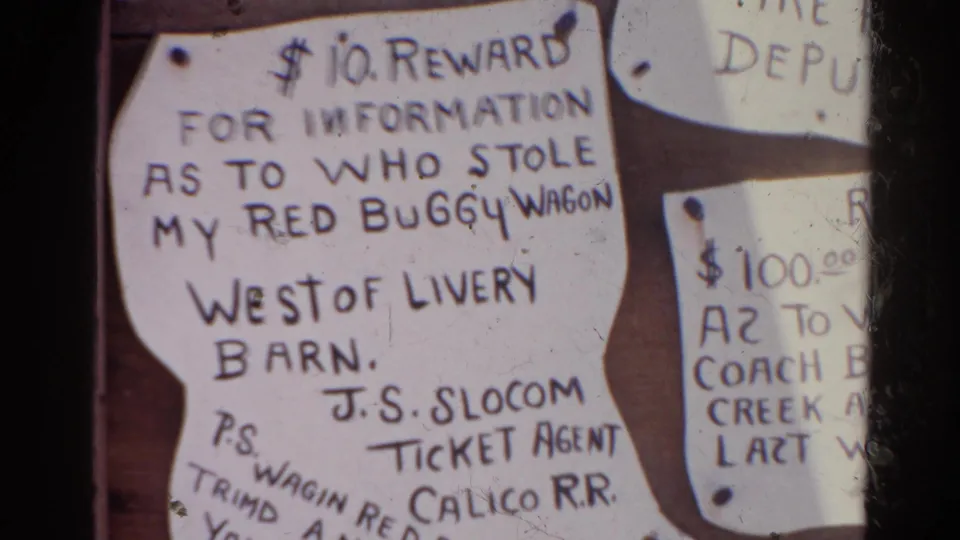 1966 Silver Lake 8mm frame showing a close bulletin-board view of a red buggy wagon reward notice and neighboring cropped notice.