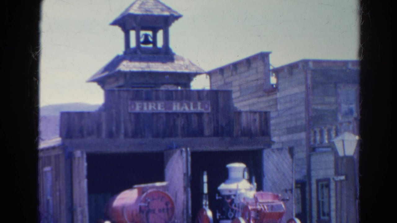 Wooden FIRE HALL facade with bell tower and red steam fire engine in the open bay.