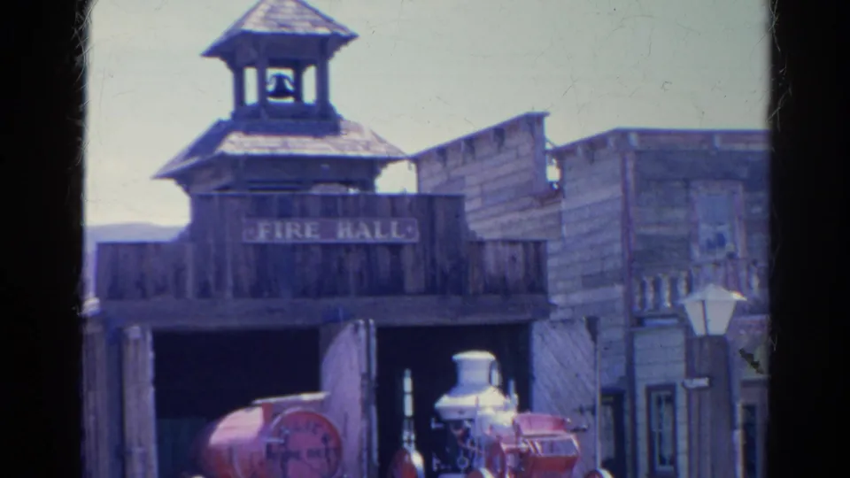 Closer 1966 Silver Lake frame of a wooden FIRE HALL facade, bell tower, open bay, and partial red steam fire engine.