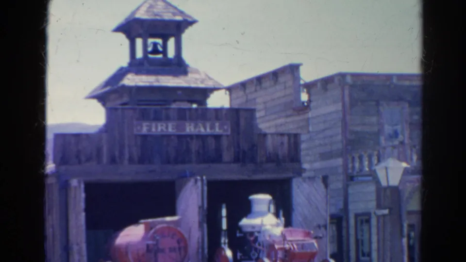 1966 Silver Lake frame showing the Old West-style fire hall, bell tower, open bay, street lamp, and red steam fire engine.