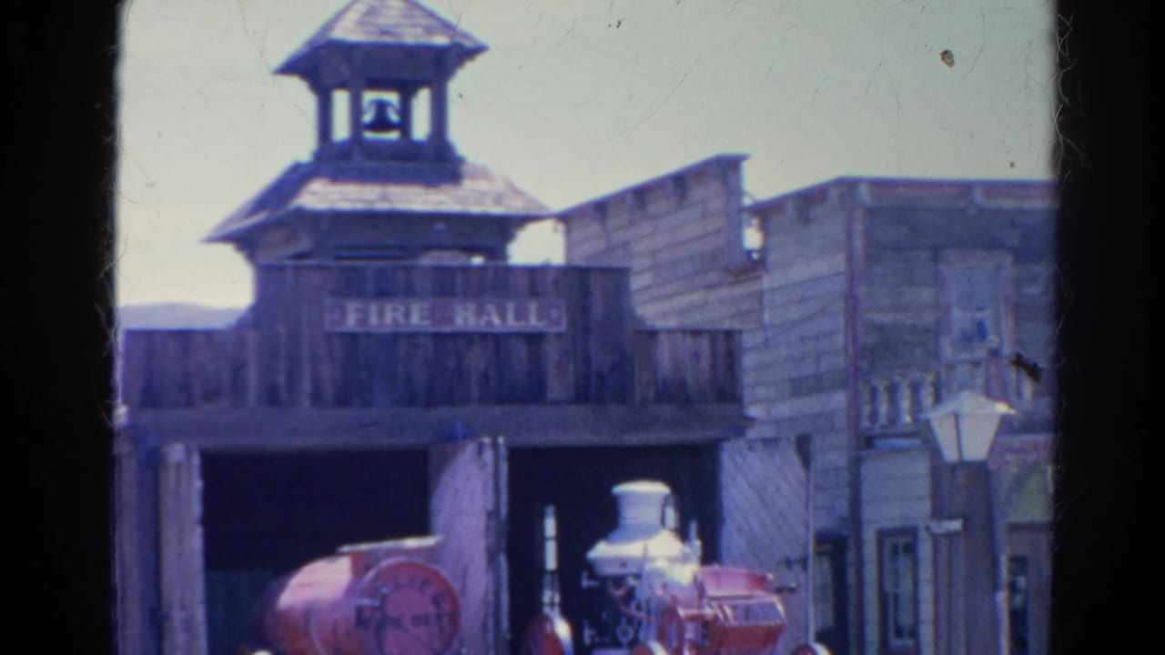 Rustic wooden fire hall with bell steeple and red fire engine visible in the open bay.