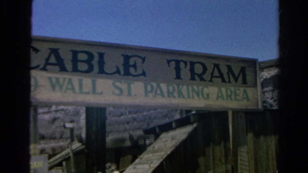 1966 Silver Lake frame with a large painted sign reading Cable Tram to Wall St. Parking Area against blue sky and timber fencing.