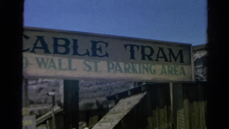 1966 Silver Lake frame with a large painted sign reading Cable Tram to Wall St. Parking Area against blue sky and timber fencing.
