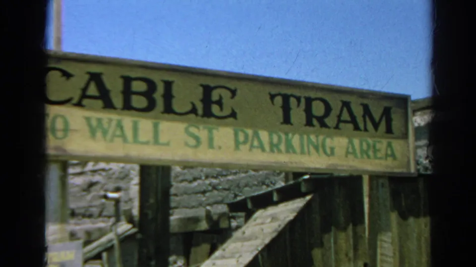 Close 1966 Silver Lake home-movie view of the Cable Tram to Wall St. Parking Area sign, framed by posts and weathered wood.