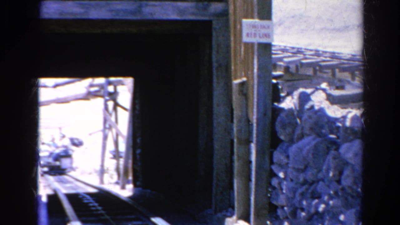 1966 Silver Lake 8mm frame showing rails inside a dark wooden tunnel, with a small tram visible in bright daylight beyond the opening.