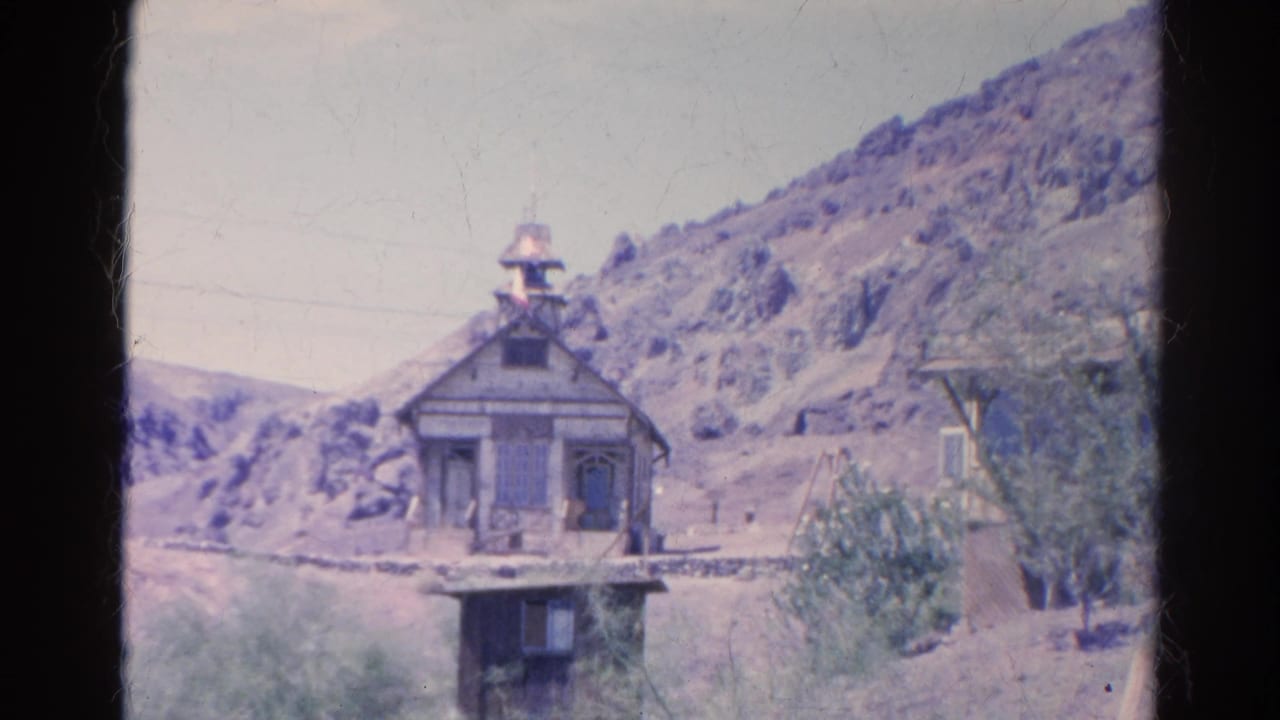 The old wooden structure appears centered in a sunlit Silver Lake desert landscape, with rocky hills and brush behind it.