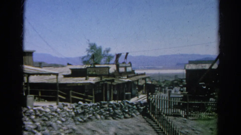 A Western-style street with signs, railings, fencing, distant lake water, and mountains appears in the 1966 Silver Lake home movie.