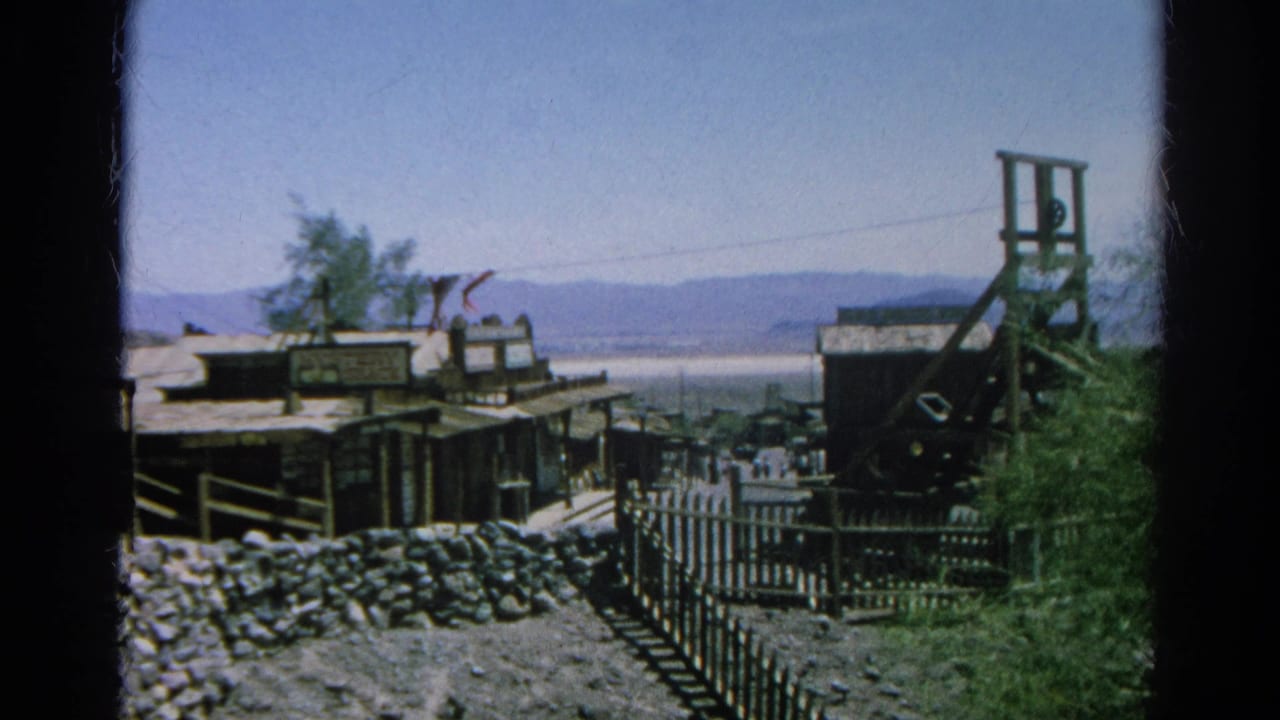 1966 Silver Lake, California home-movie frame showing rustic Western buildings, fencing, and a mine-shaft structure under clear sky.