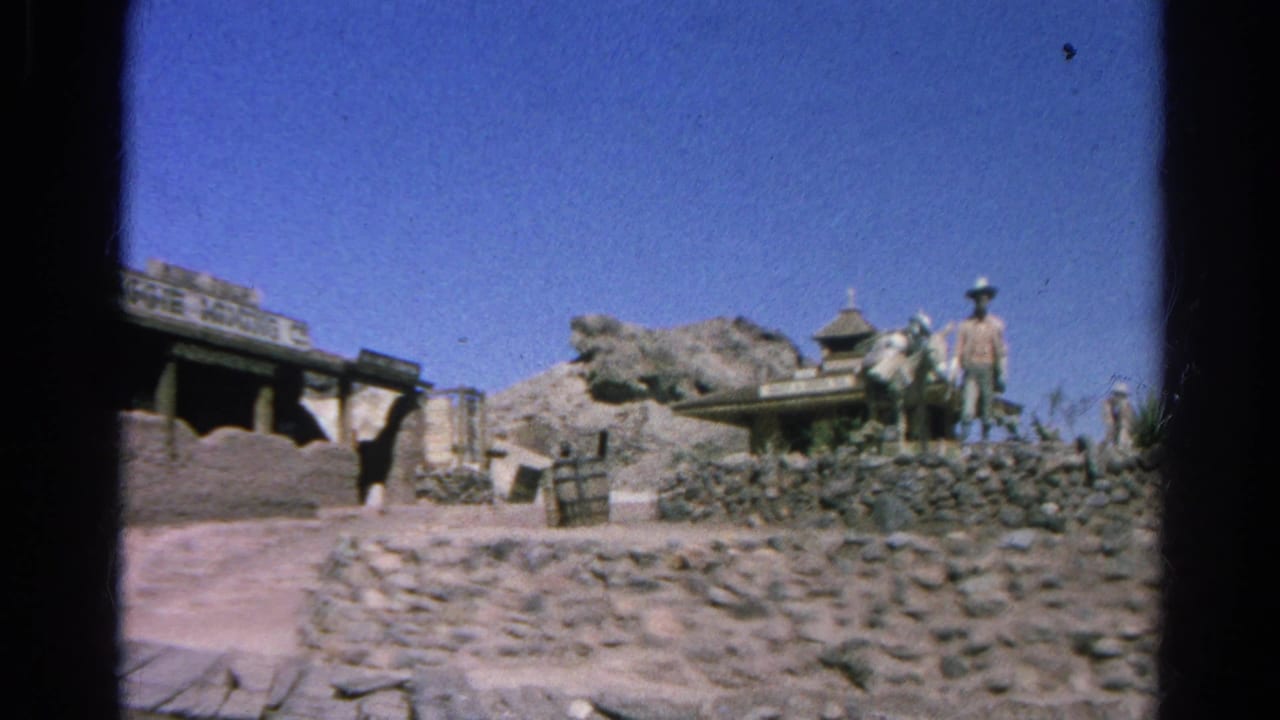 1966 Silver Lake frame with a stone-walled Western set, rocky terrain, horse-drawn wagon, and a cowboy-hatted man under bright sky.