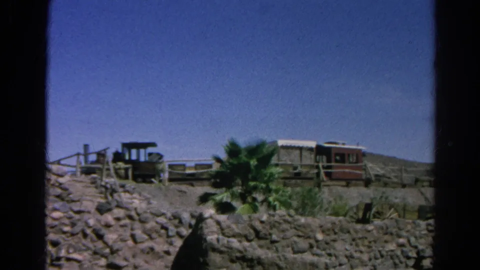 Silver Lake, California 1966 frame showing a Western-style attraction area with train cars, palms, fencing, and rocky landscaping.