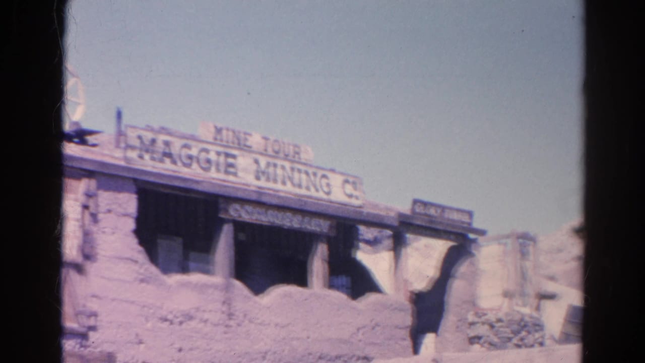 Weathered Maggie Mining Co. mine tour entrance with signage, rockwork, and a water wheel.