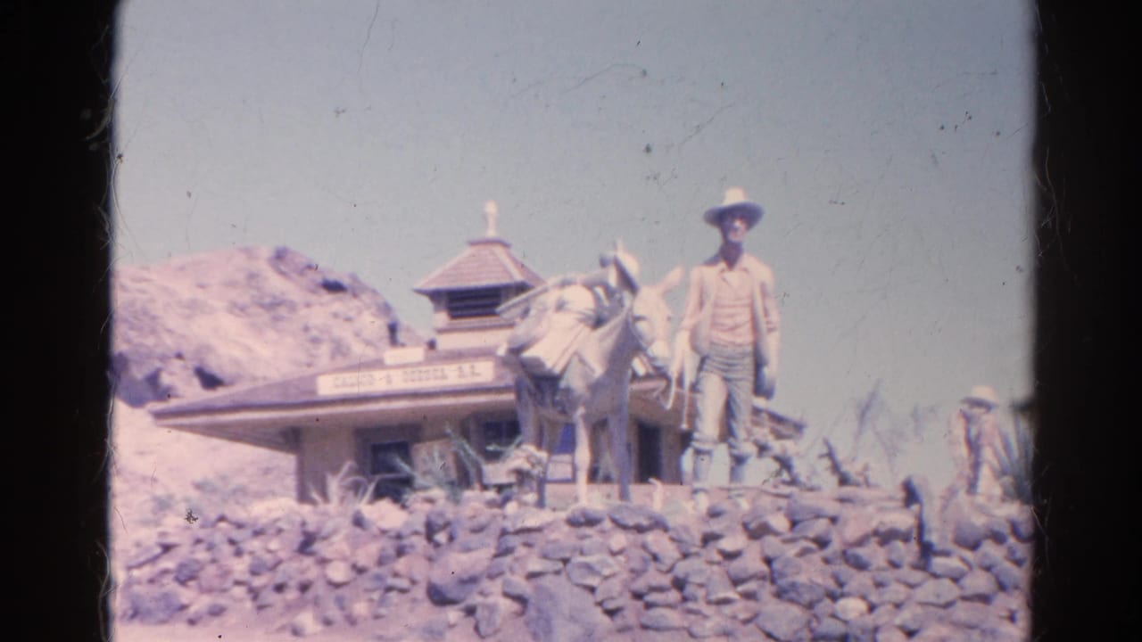 1966 Silver Lake, California home-movie frame showing a cowboy figure beside a donkey statue in front of a small themed building and rocks.