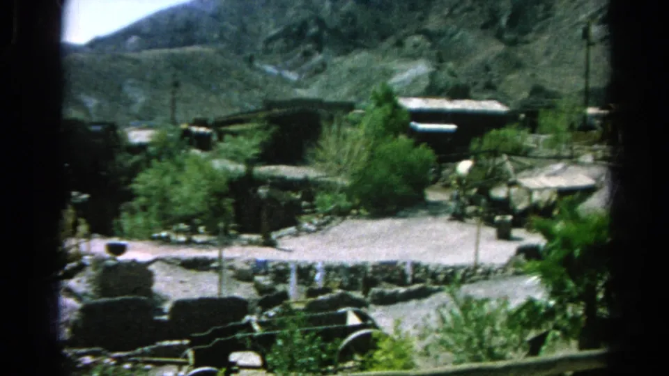 1966 Silver Lake, California frame showing a quiet roadside area with low walls, scrub plants, fencing, small structures, and hills in the background.
