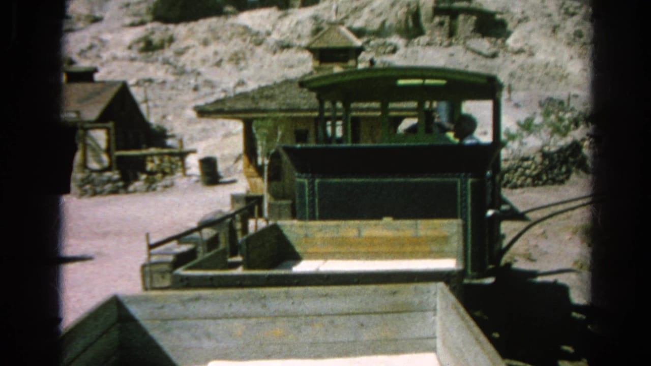 A small green train or tram car stands by a platform in the 1966 Silver Lake Western-style mining town footage.