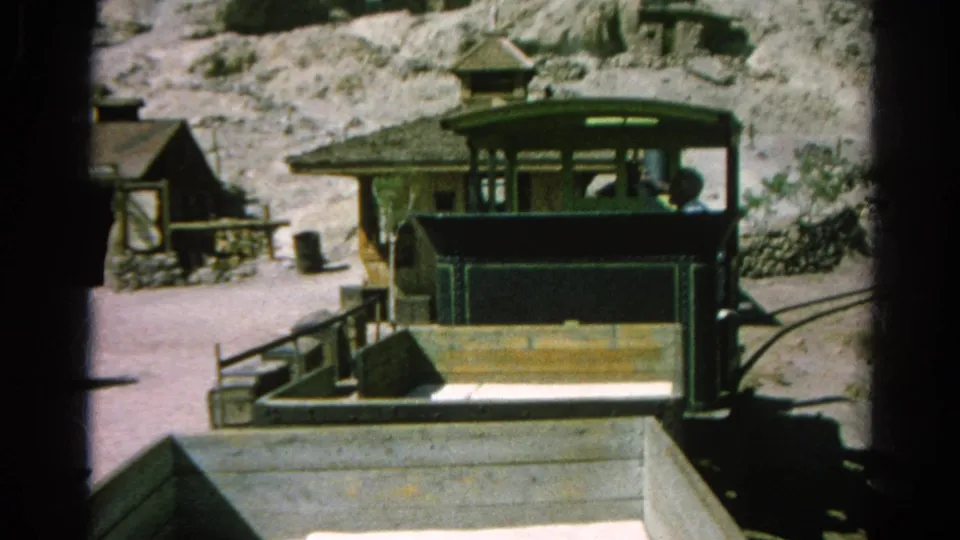 A small green train or tram car stands by a platform in the 1966 Silver Lake Western-style mining town footage.