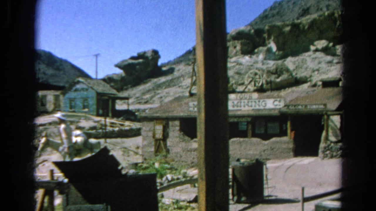 Silver Lake, California home-movie frame showing a Western mining facade, mine tower, rocky hillside, and a visitor in a cowboy hat.