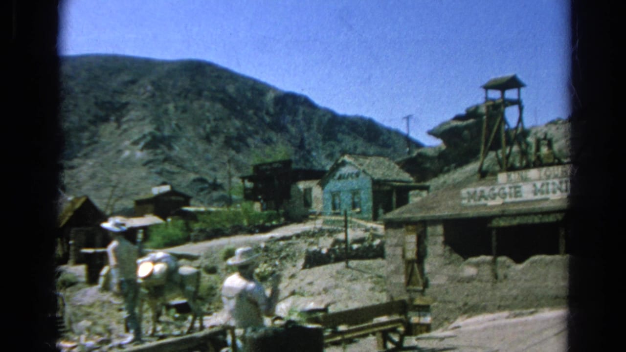 1966 8mm frame widens to show Silver Lake Western-style buildings, mountain backdrop, mine tower, and visitors along the dirt road.