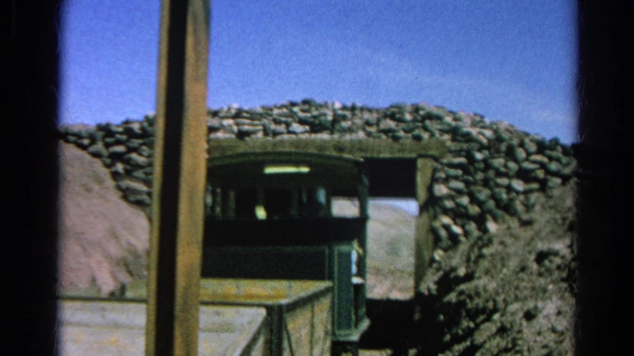 Green train car near a stone-lined tunnel portal in Silver Lake, California, with a timber post, dirt slope, and rough rockwork visible in the 1966 8mm frame.