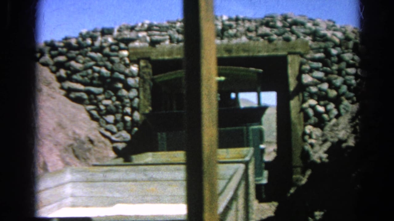Close 1966 8mm view of the small green train passing into a stone-lined tunnel at Silver Lake, partly obscured by a vertical timber post and foreground car edge.