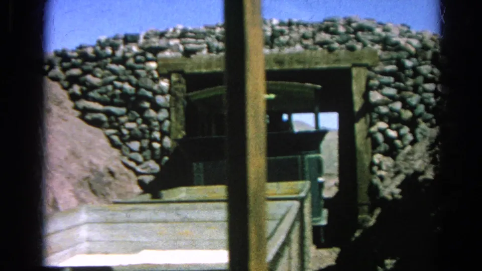 Close 1966 8mm view of the small green train passing into a stone-lined tunnel at Silver Lake, partly obscured by a vertical timber post and foreground car edge.